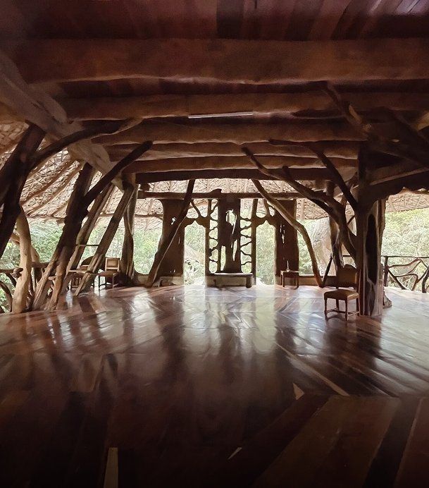 Interior de la Shala: piso de madera pulida y estructura de troncos abierta a la selva
